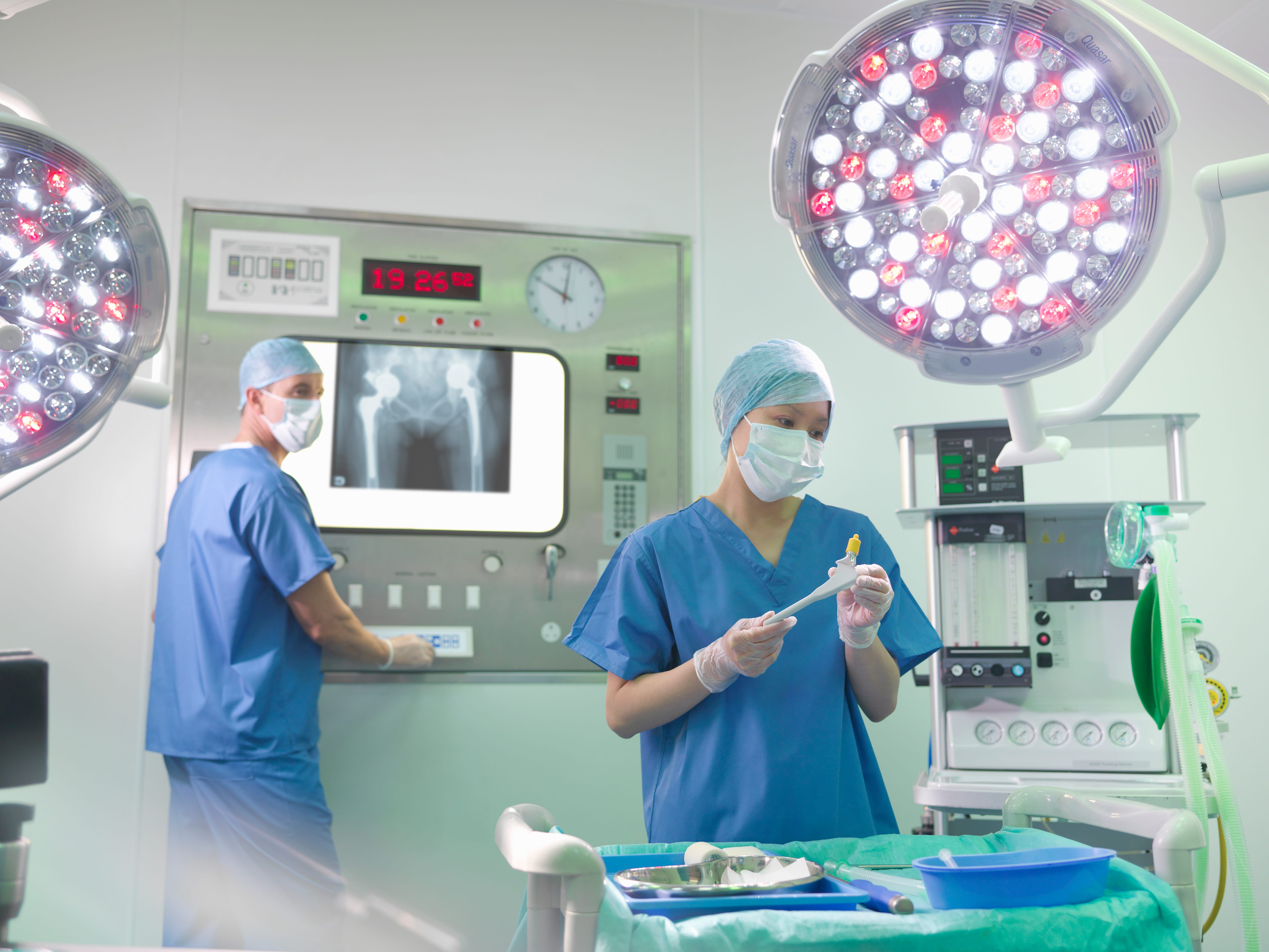 Orthopaedic surgeon and nurse with replacement hip stem in operating theatre