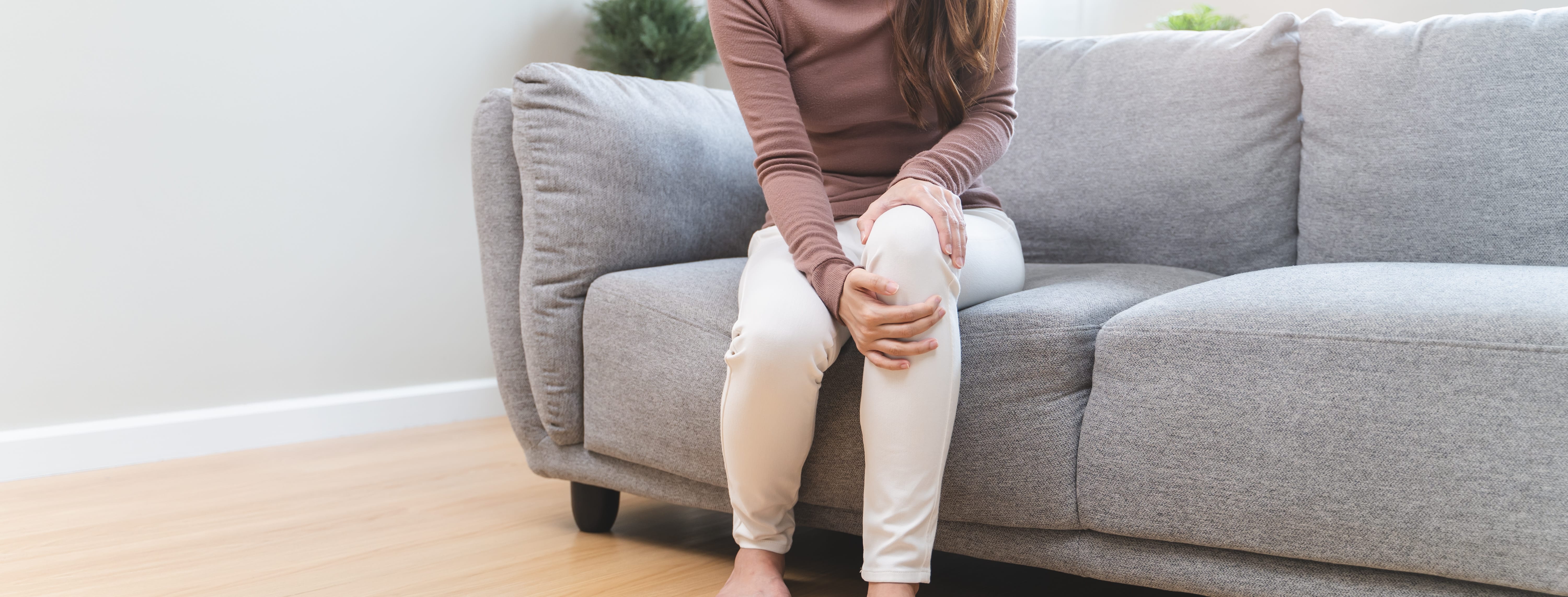 Young Asian woman touching her knee feel pain when move.