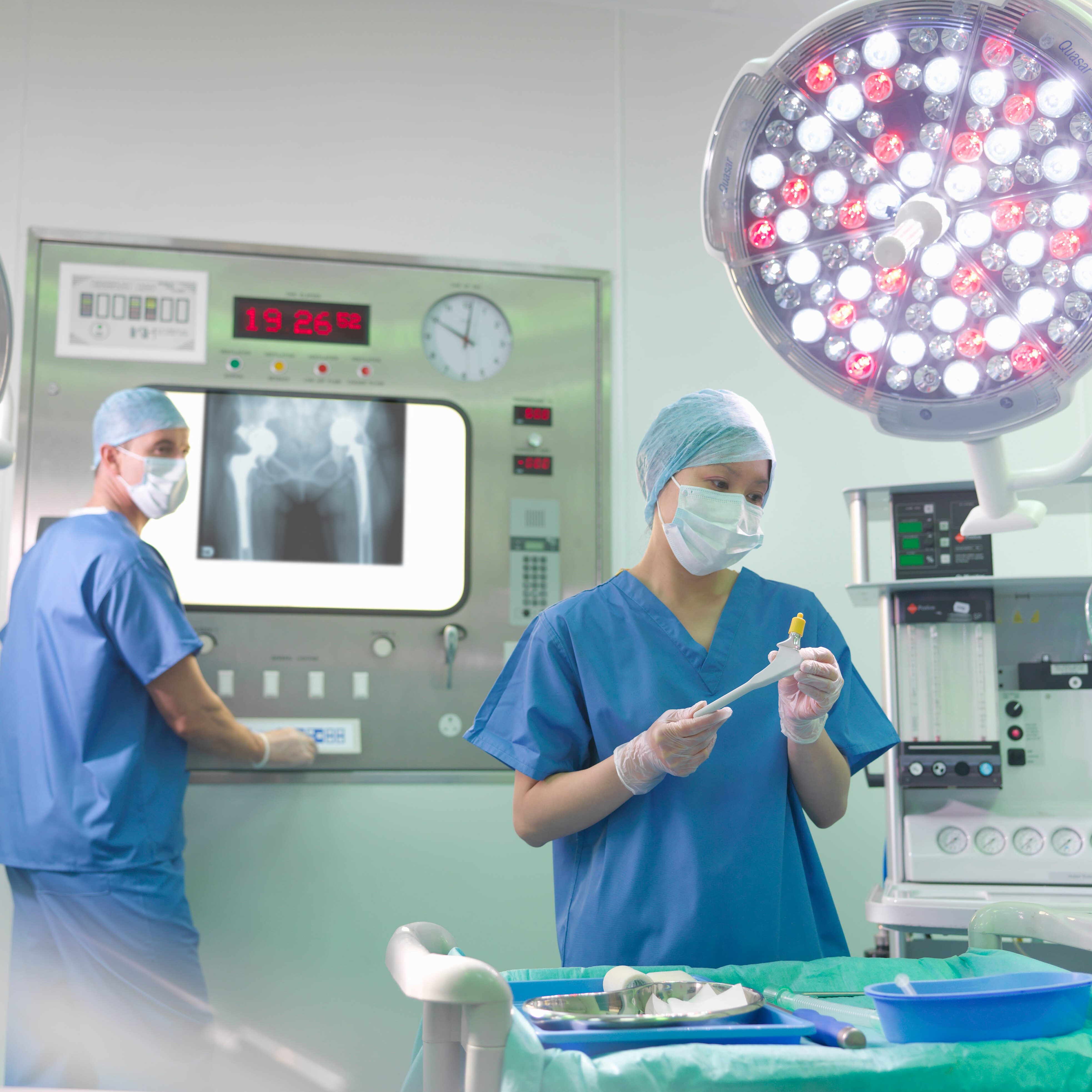 Orthopaedic surgeon and nurse with replacement hip stem in operating theatre