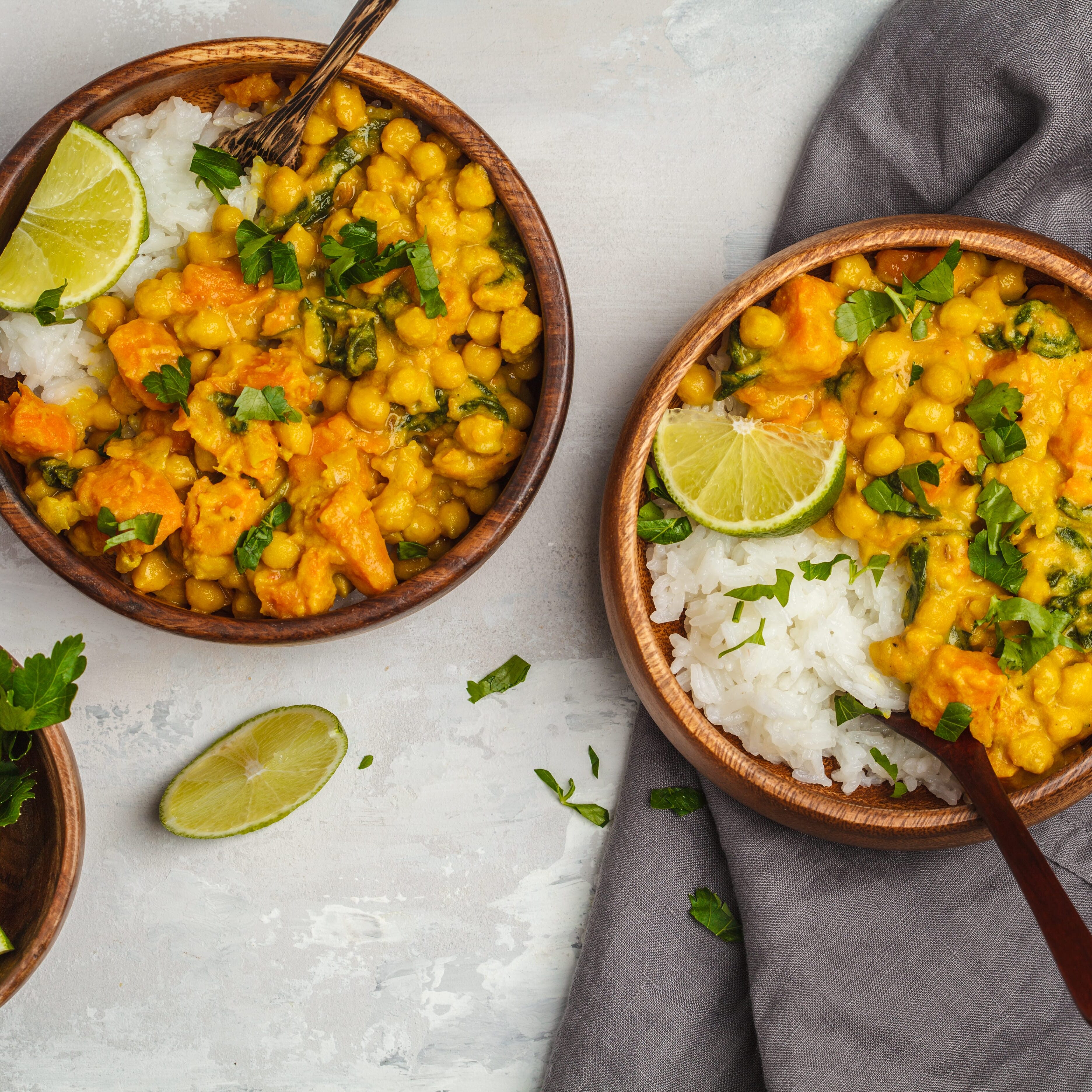 Vegan Sweet Potato Chickpea curry in wooden bowl on a light background, top view, copy space. Healthy vegetarian food concept.